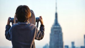 Boy looking through the binoculars at New York city